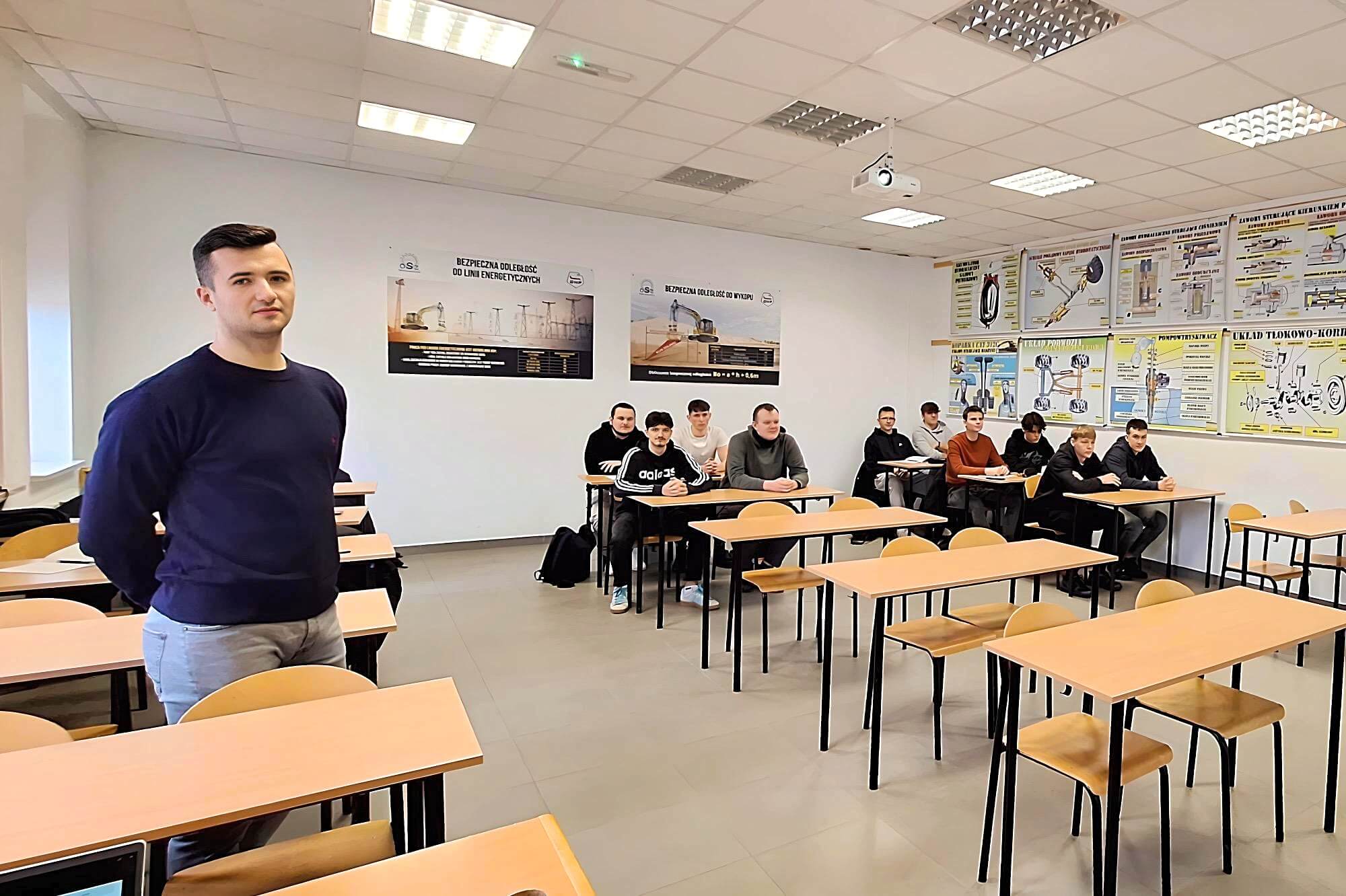 Mężczyzna stoi przed studentami w sali wykładowej