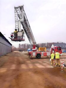 Strażacy ćwiczą na podnośniku hydraulicznym.